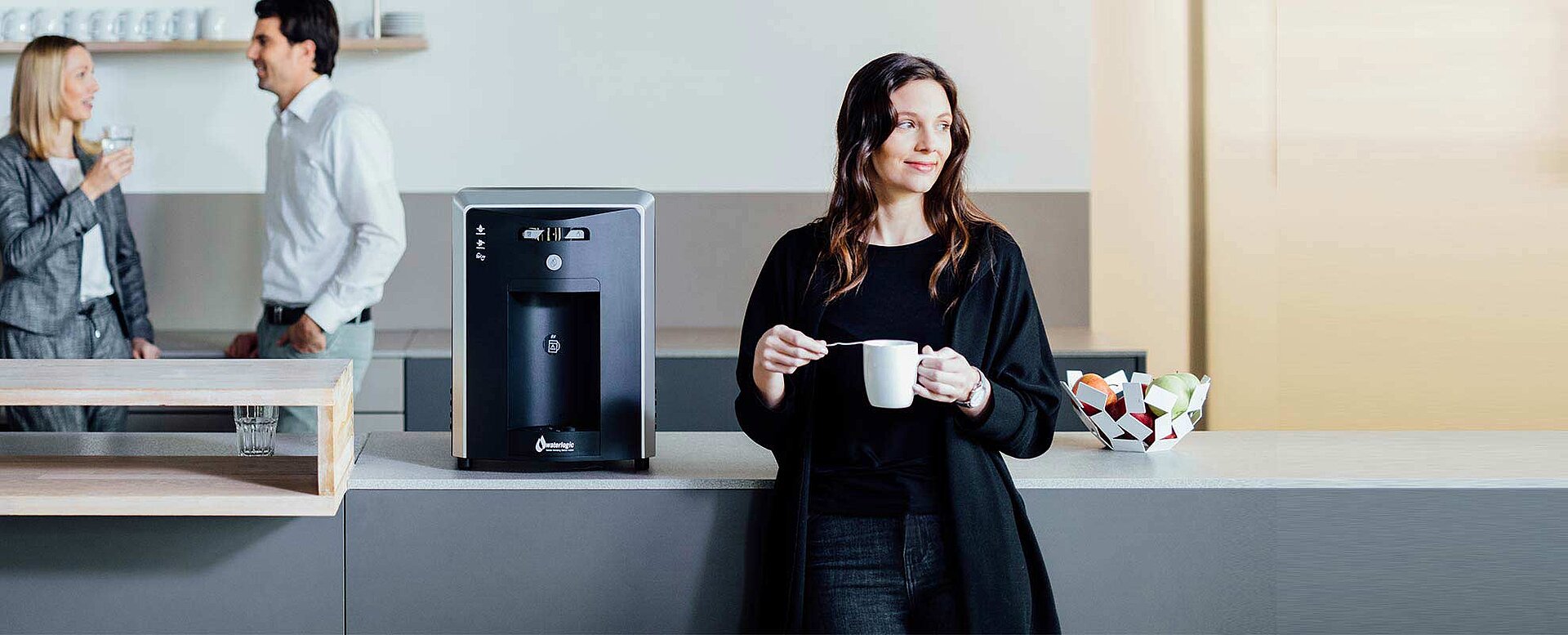 Woman by hot water dispenser drinking tea